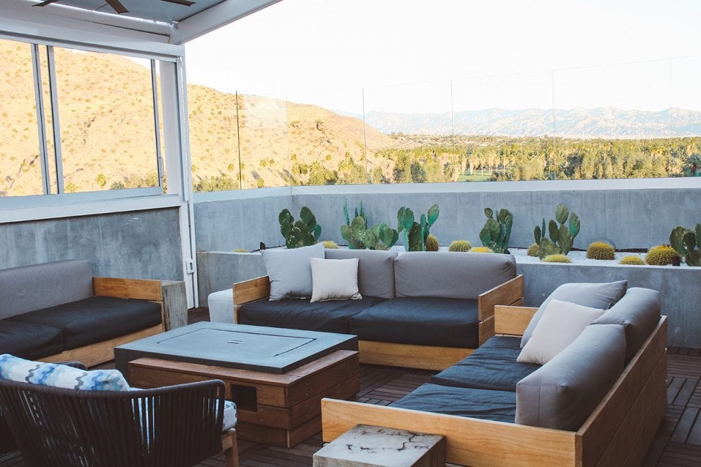 roof top lounge area overlooking palm trees and mountains in Palm Springs